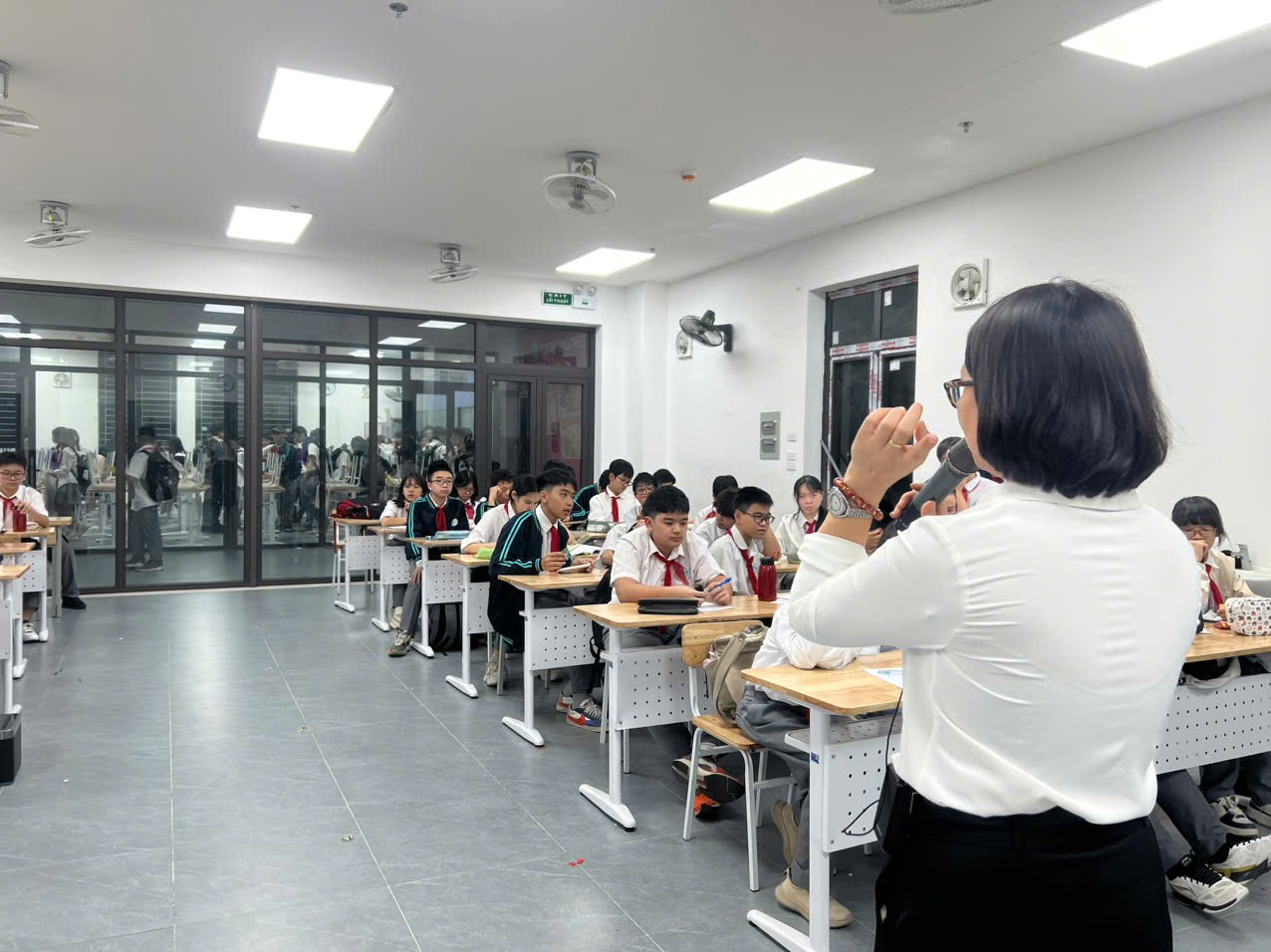 A person in a white shirt speaking to a group of studentsAI-generated content may be incorrect.