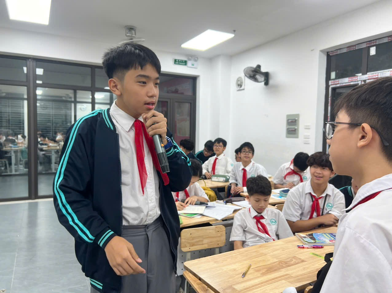 A child speaking into a microphone in a classroomAI-generated content may be incorrect.