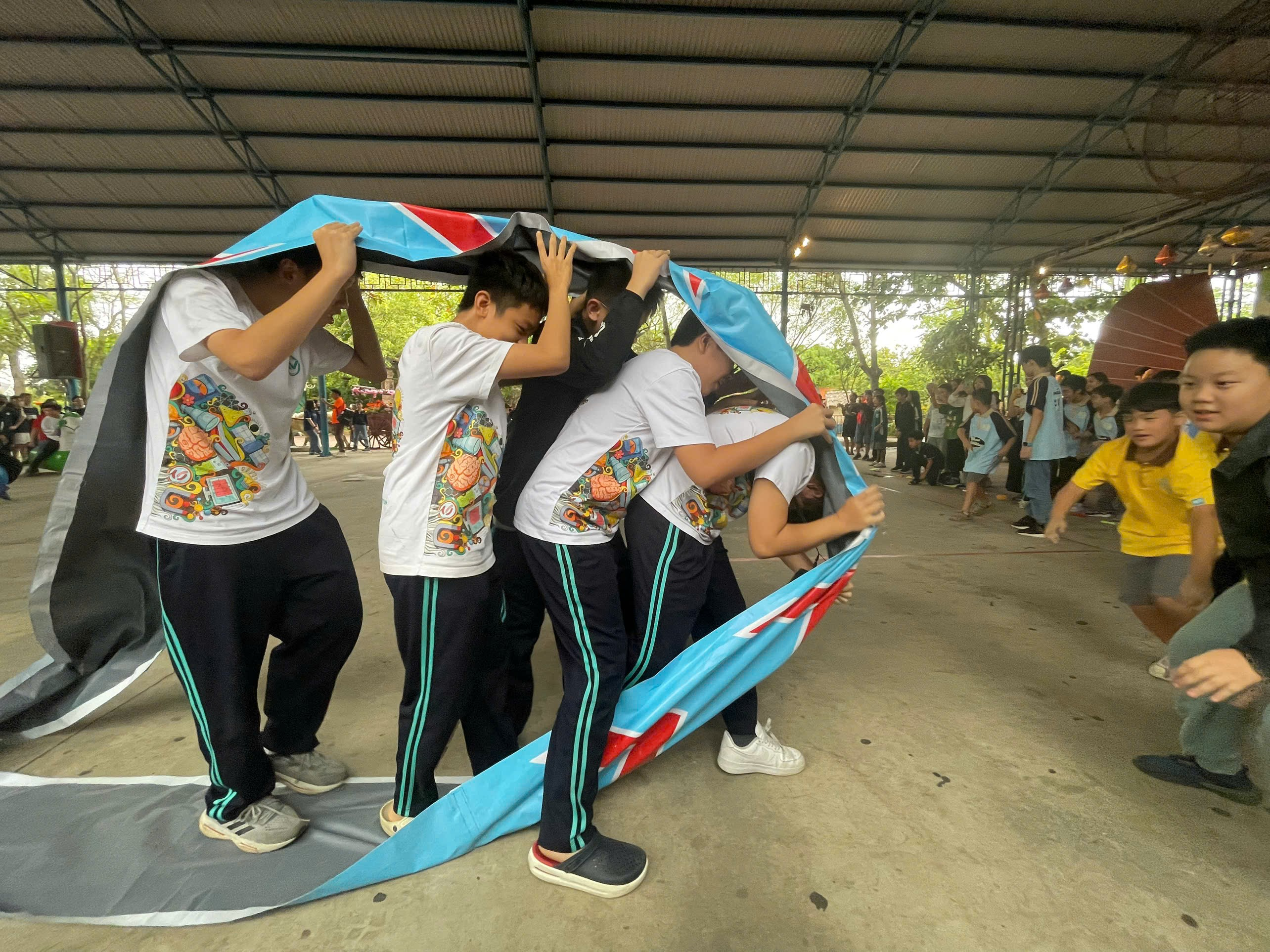 A group of people holding up a blue blanketAI-generated content may be incorrect.