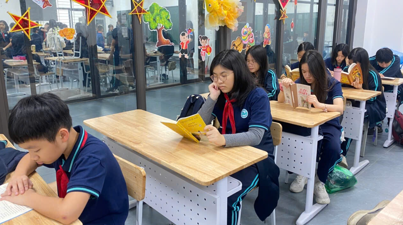 A group of people sitting at desks reading booksAI-generated content may be incorrect.