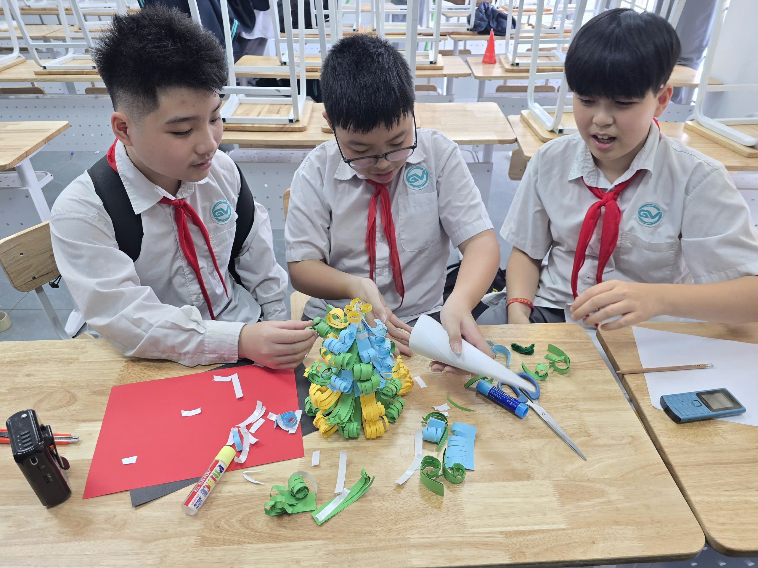 A group of boys in uniform sitting at a table making paper craftsDescription automatically generated