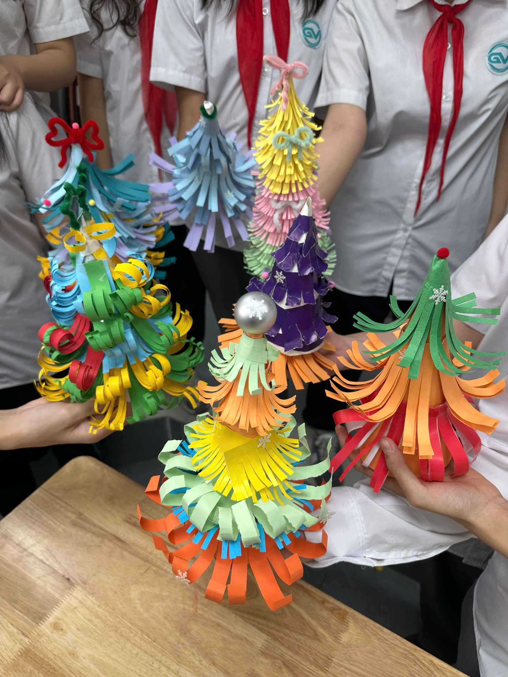 A group of people holding paper treesDescription automatically generated