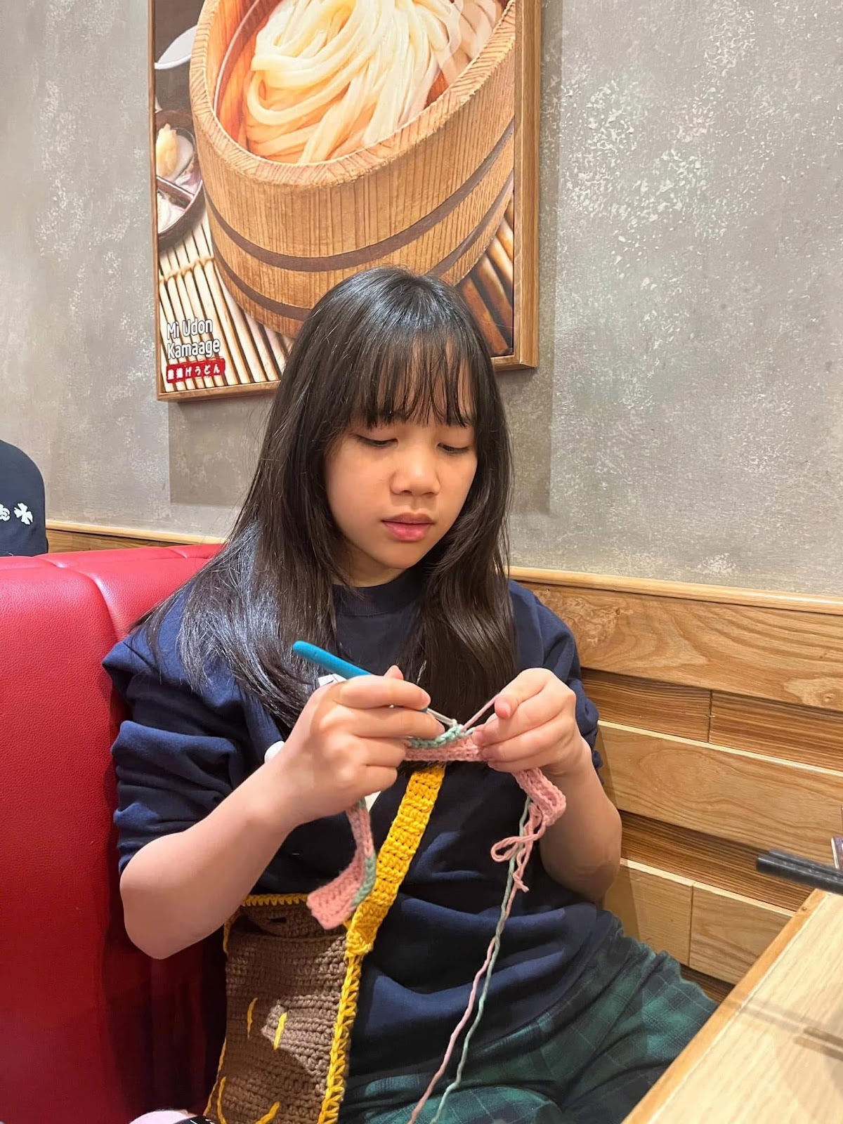 A child sitting at a table knittingAI-generated content may be incorrect.