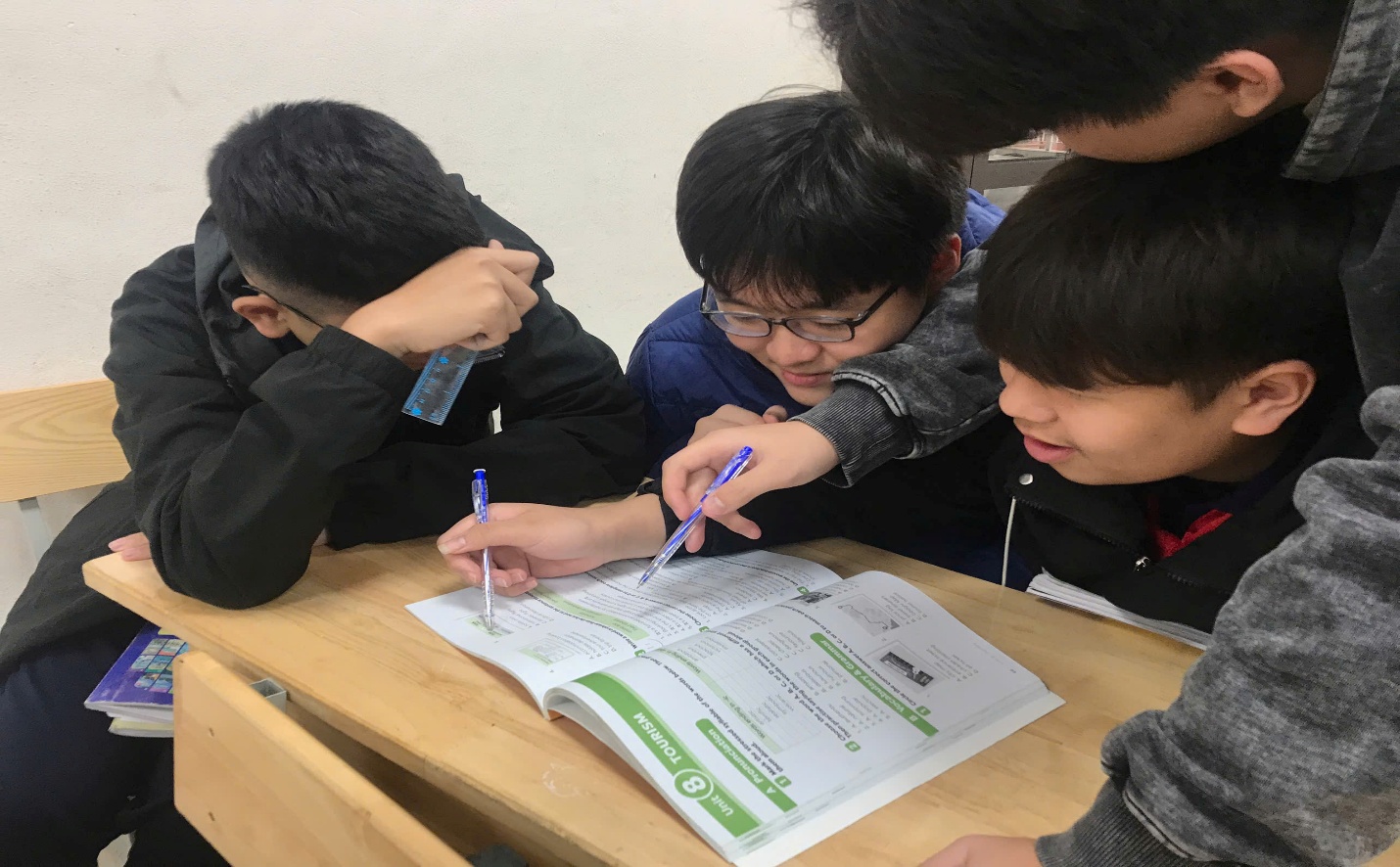 A group of people looking at a bookAI-generated content may be incorrect.