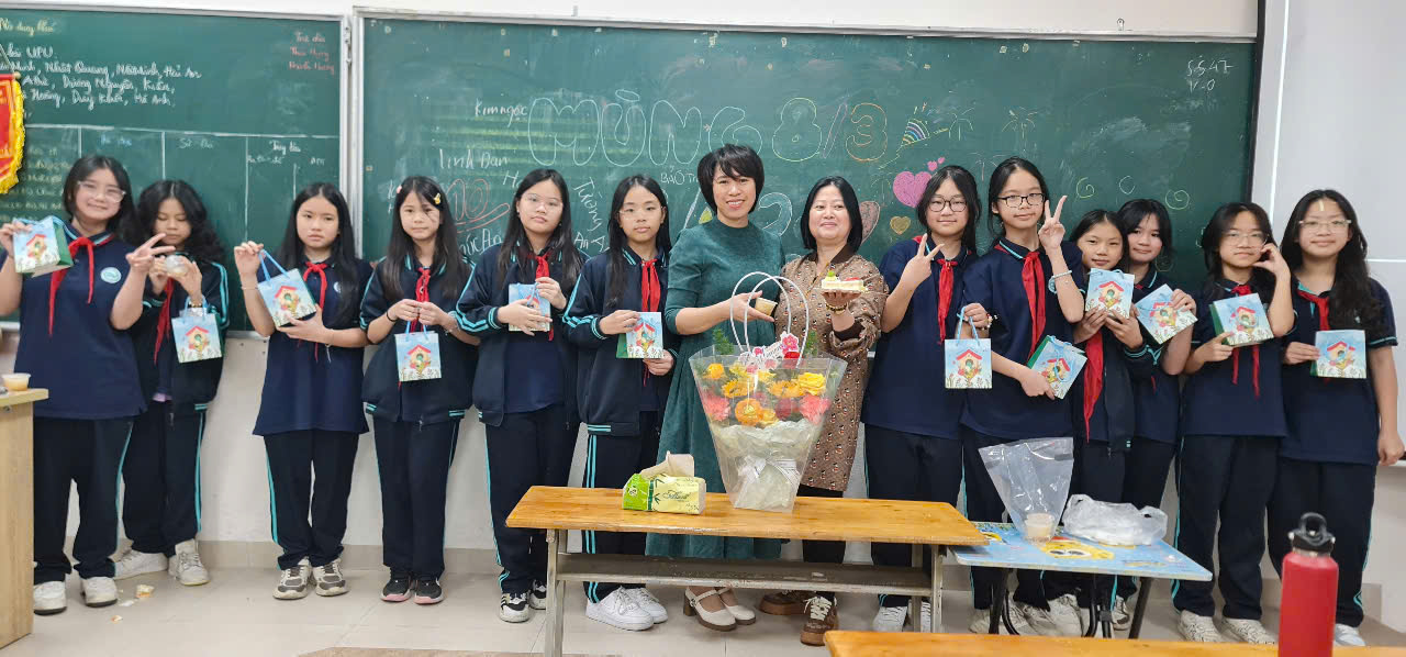 A group of people standing in front of a chalkboardDescription automatically generated