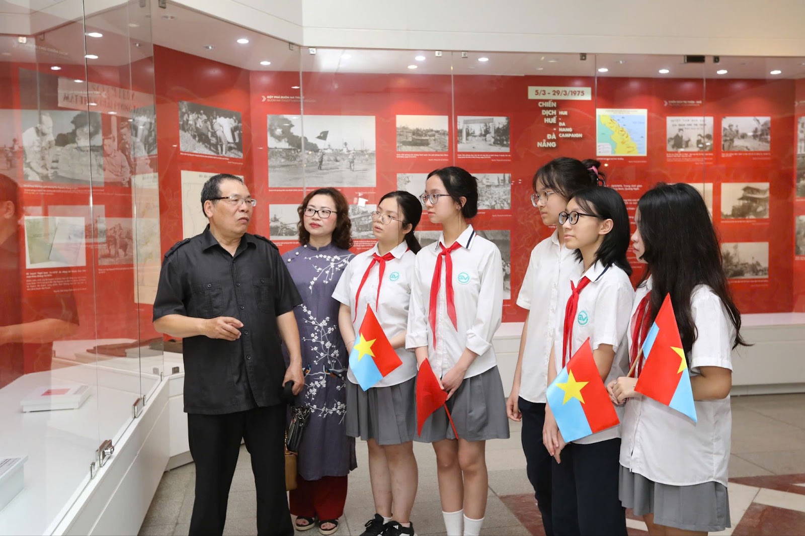 A group of people standing in a room with red wallsAI-generated content may be incorrect.