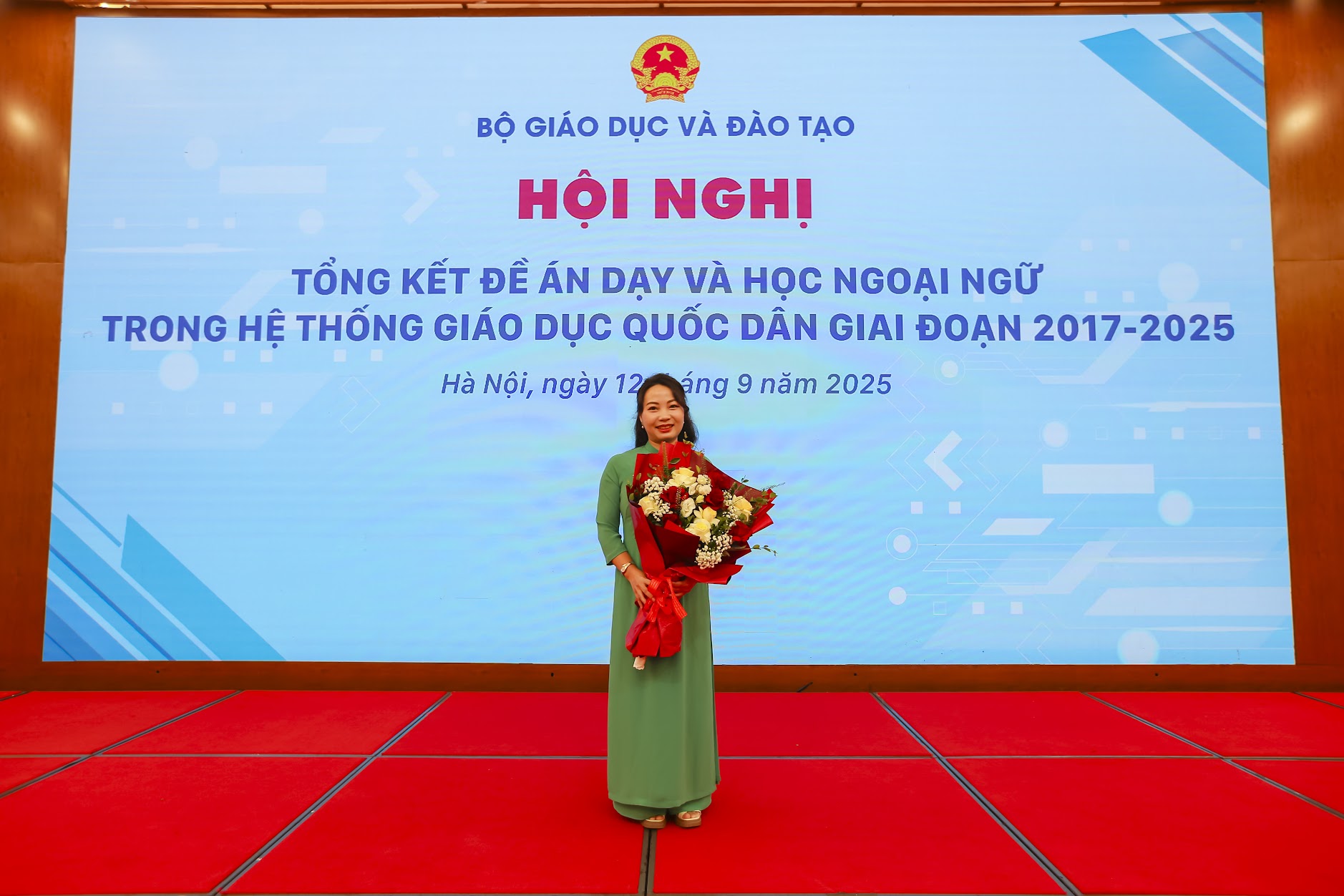 A person standing on a red carpet holding flowersAI-generated content may be incorrect.