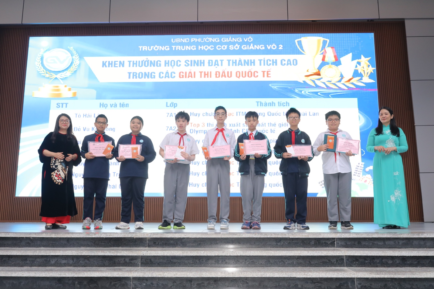 A group of people standing on a stage holding certificatesDescription automatically generated