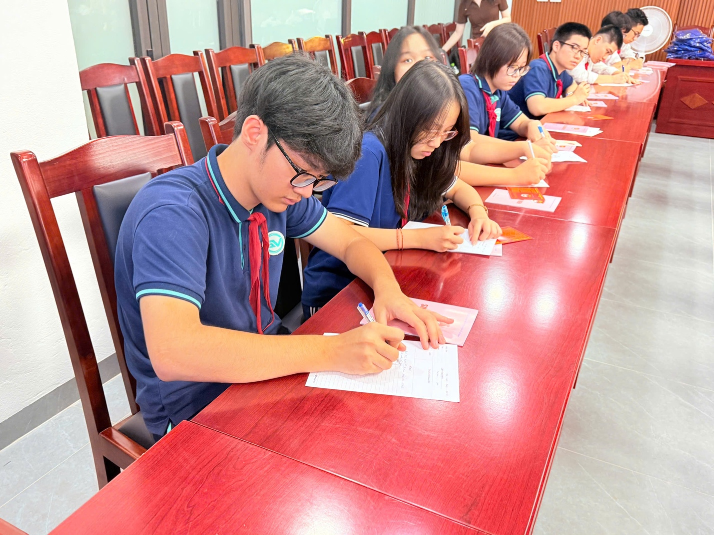 A group of people sitting at a table writing on paperDescription automatically generated