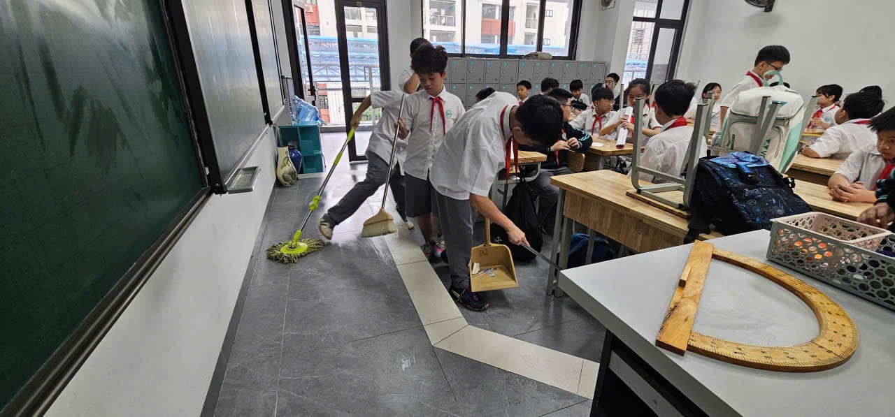 A group of students cleaning the floorDescription automatically generated