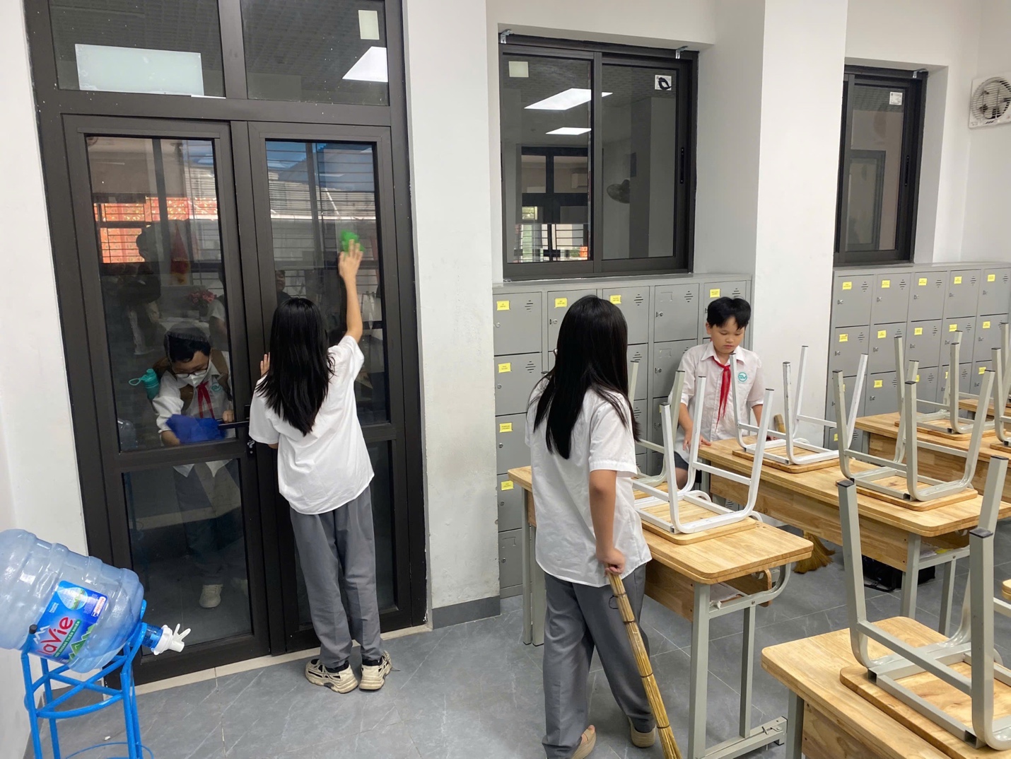 A group of people cleaning a classroomDescription automatically generated
