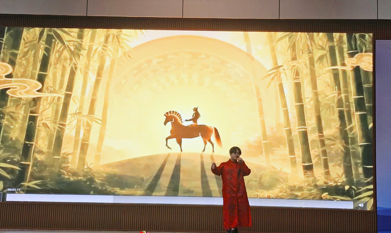 A person in a red robe standing in front of a large screenDescription automatically generated